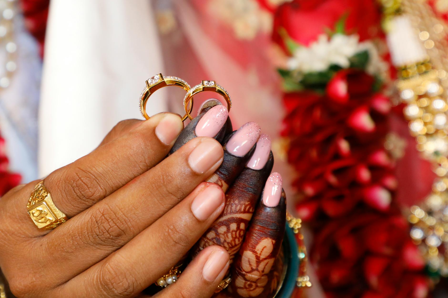 Close-up of hands holding gold wedding rings with intricate henna, showcasing love and union. - new marriage adjustments