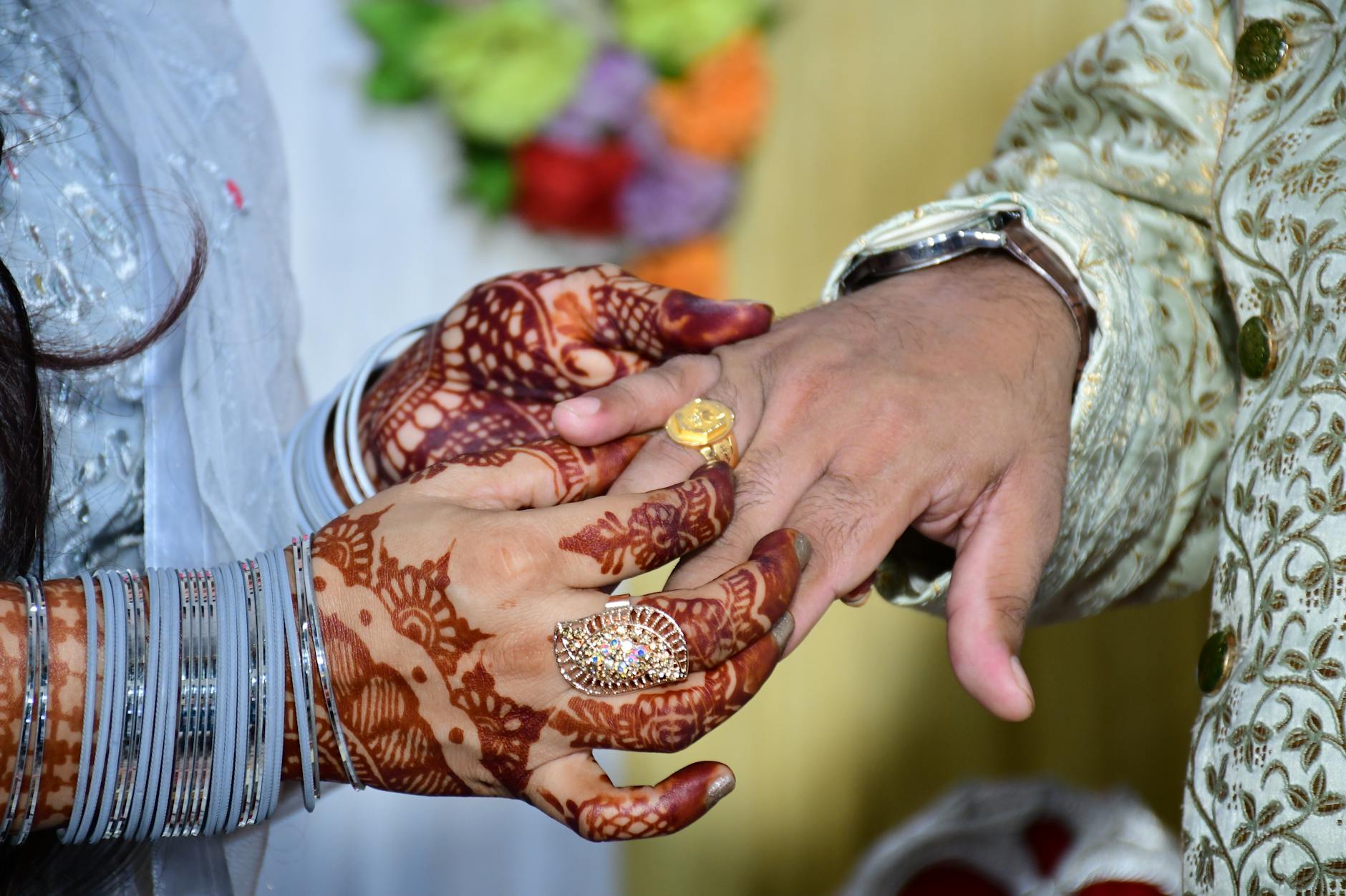 Close-up of a bride and groom exchanging rings, showcasing intricate henna, in an Indian wedding in New Delhi. - new marriage adjustments