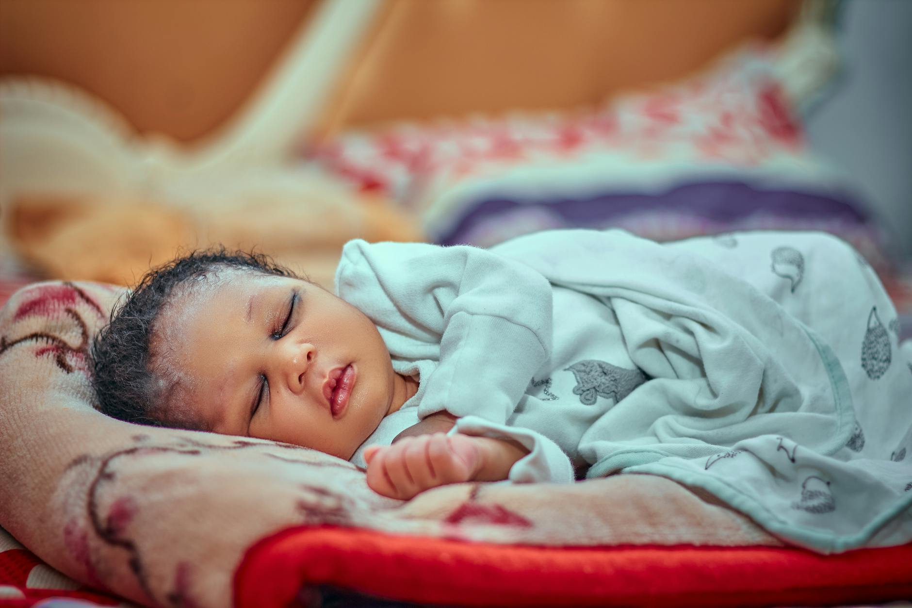 A serene image of a sleeping baby wrapped in a soft blanket indoors. - new parent sleep