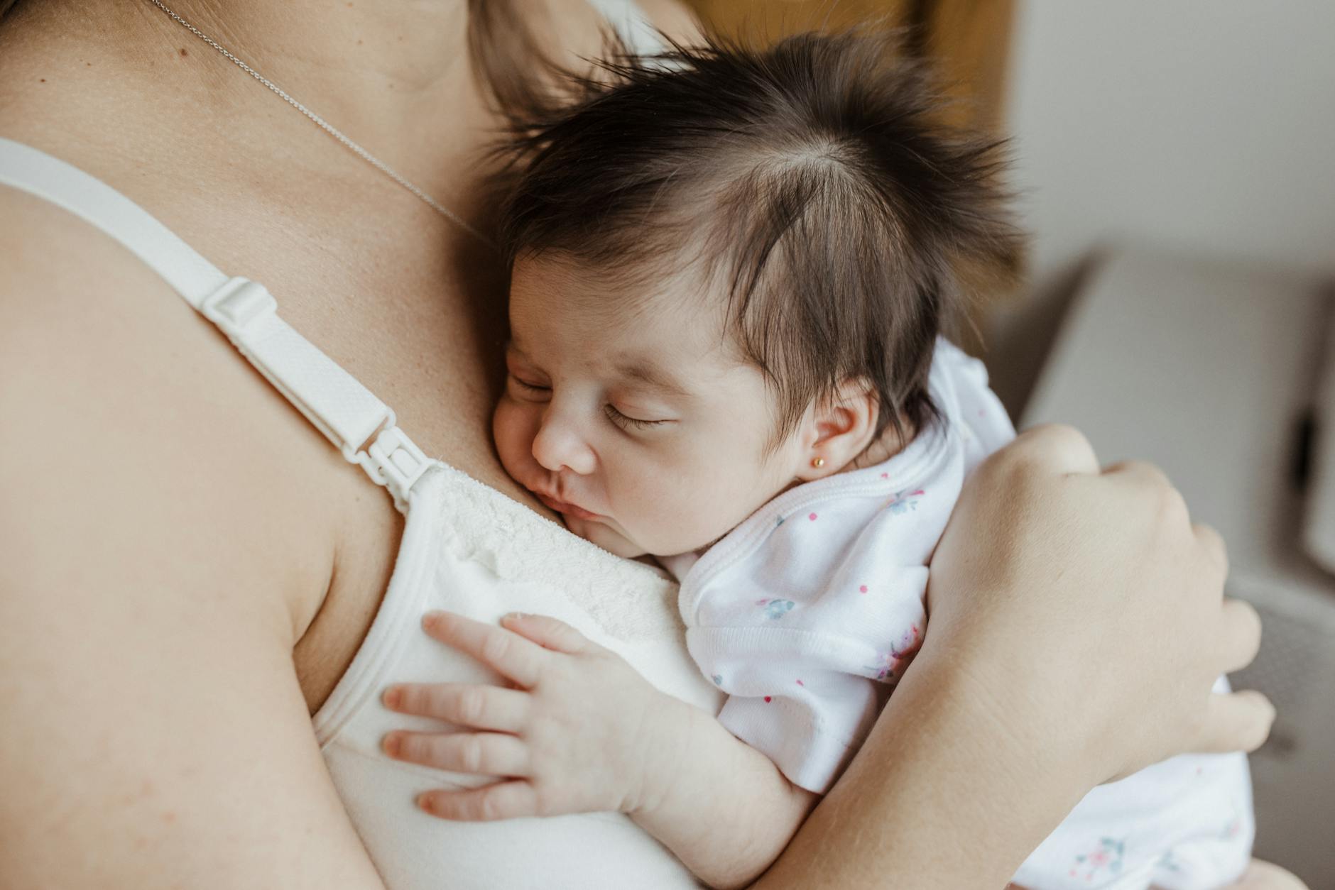 A tender moment with a newborn sleeping peacefully on their mother's chest, showcasing the bond of love. - new parent sleep