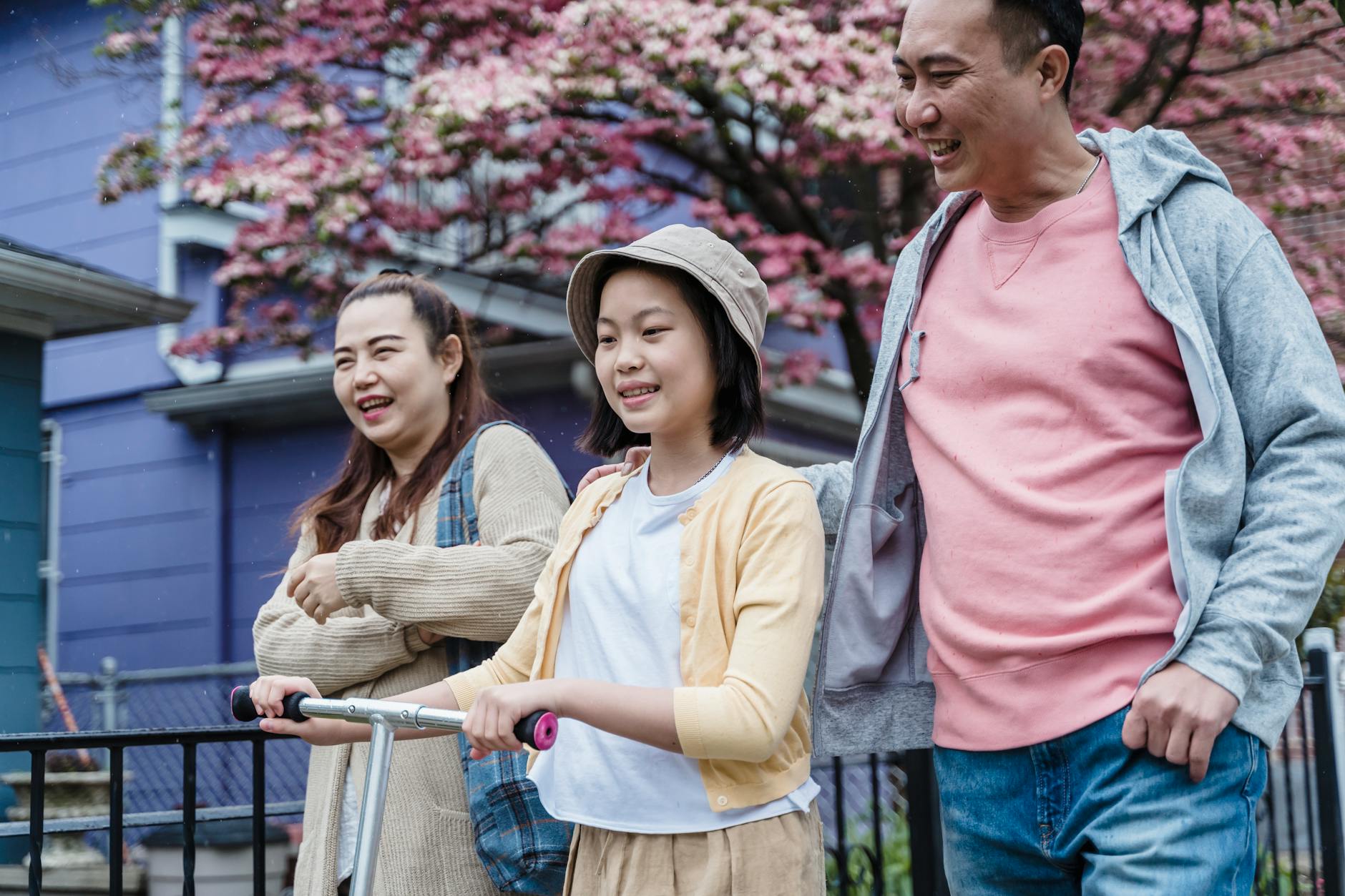Happy family walking together outdoors by blooming cherry blossoms. - parent burnout spring