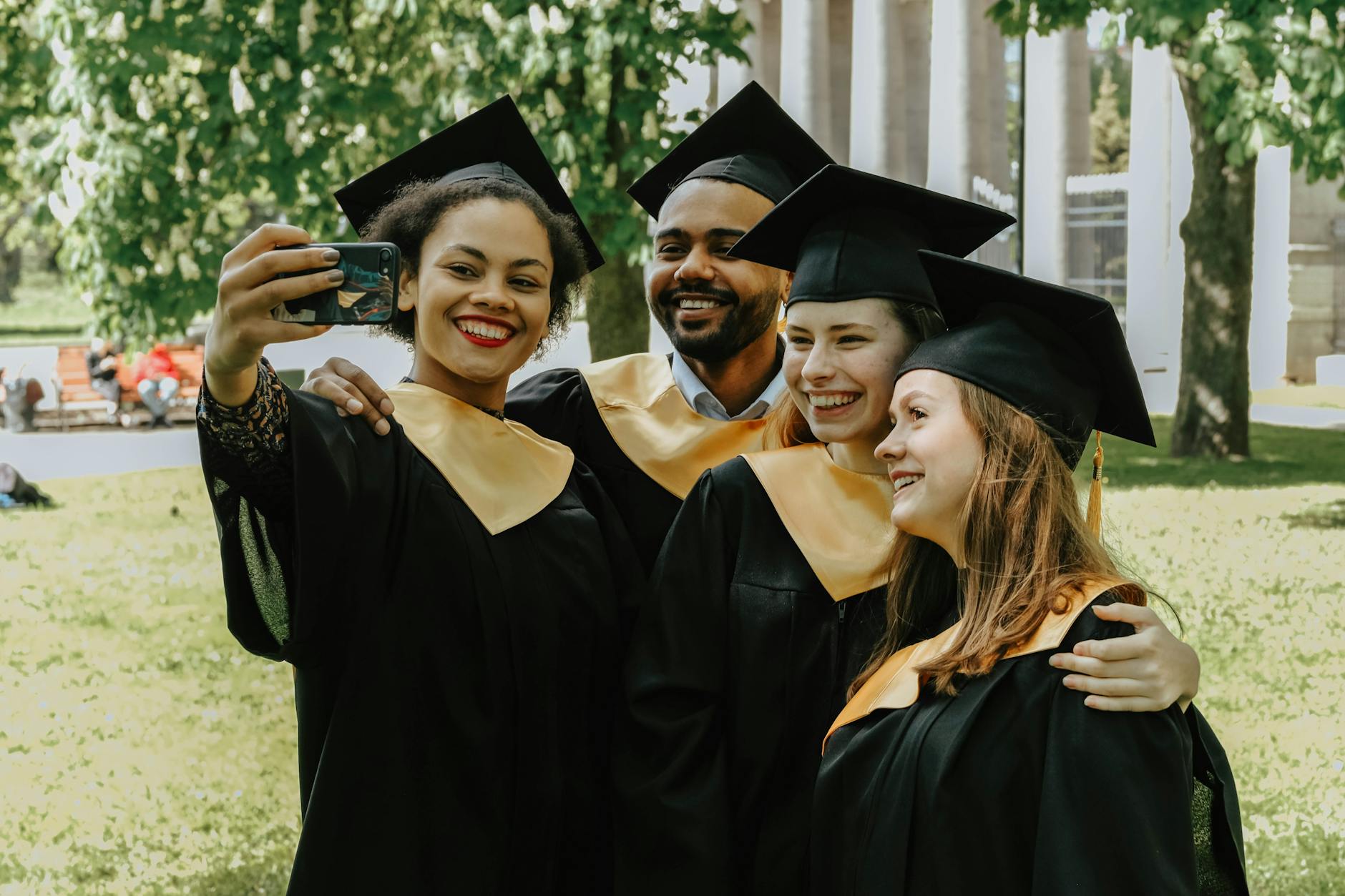 Group of diverse college graduates taking a selfie in their caps and gowns outdoors. - post grad relationships