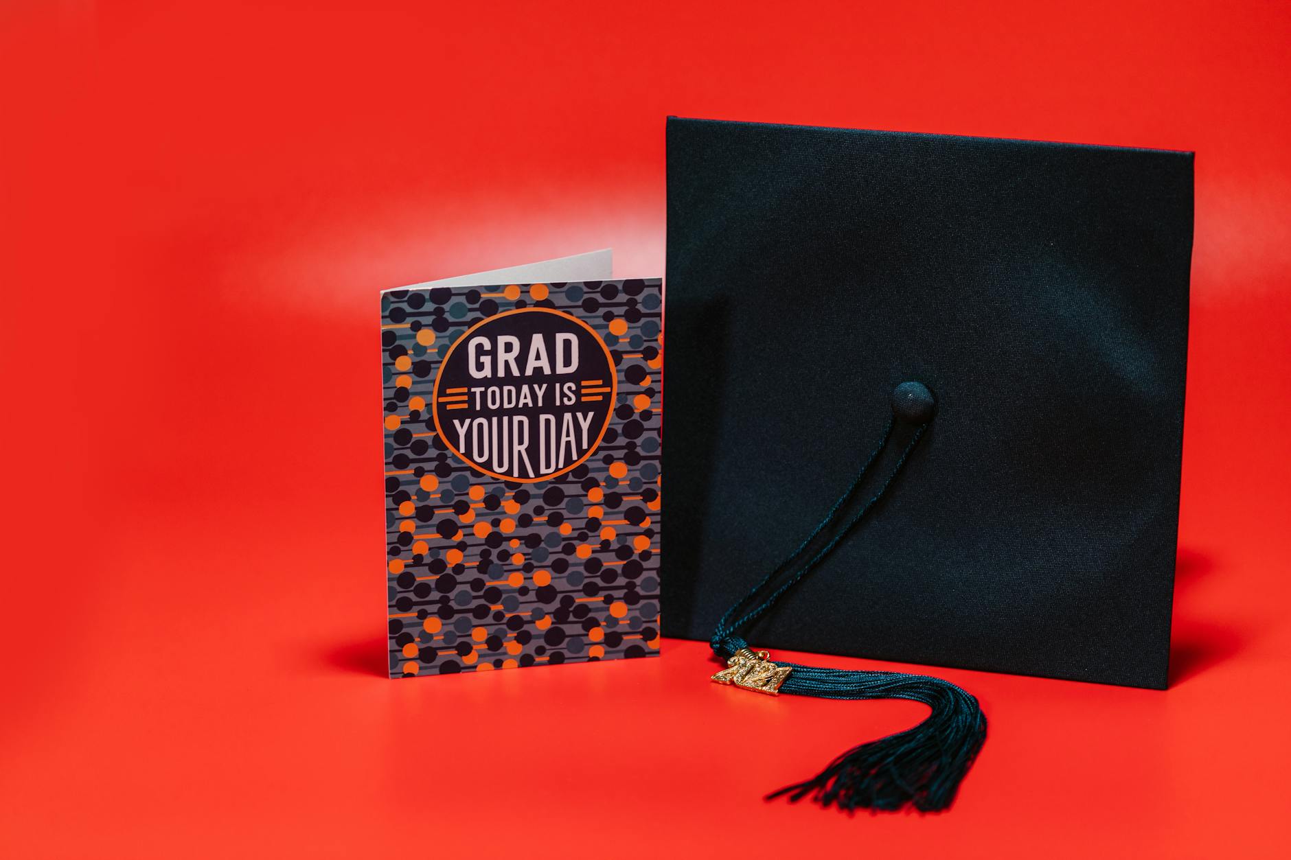 Graduation cap and card against a bold red background, celebrating achievement. - post grad resilience