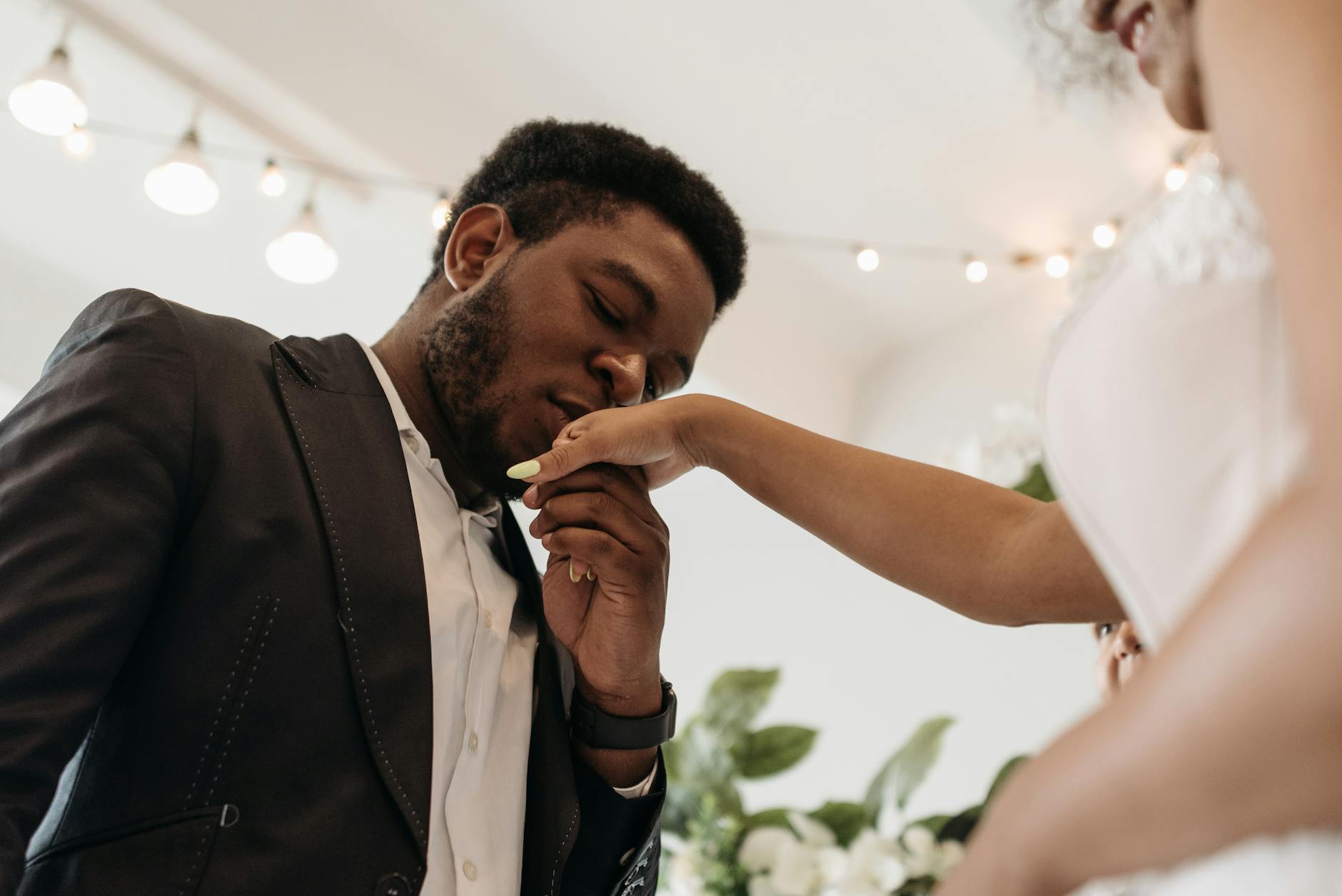 A tender moment during a wedding ceremony where the groom kisses the bride's hand, symbolizing love and commitment. - post wedding connection