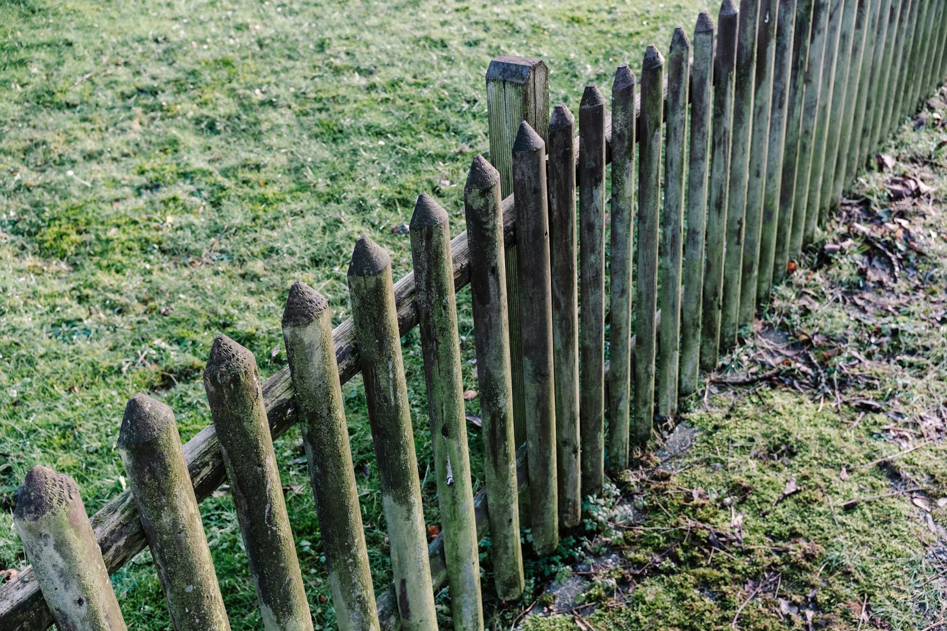 A rustic, weathered wooden fence in a grassy, outdoor garden setting. Perfect for nature photography. - preschool boundaries outdoors