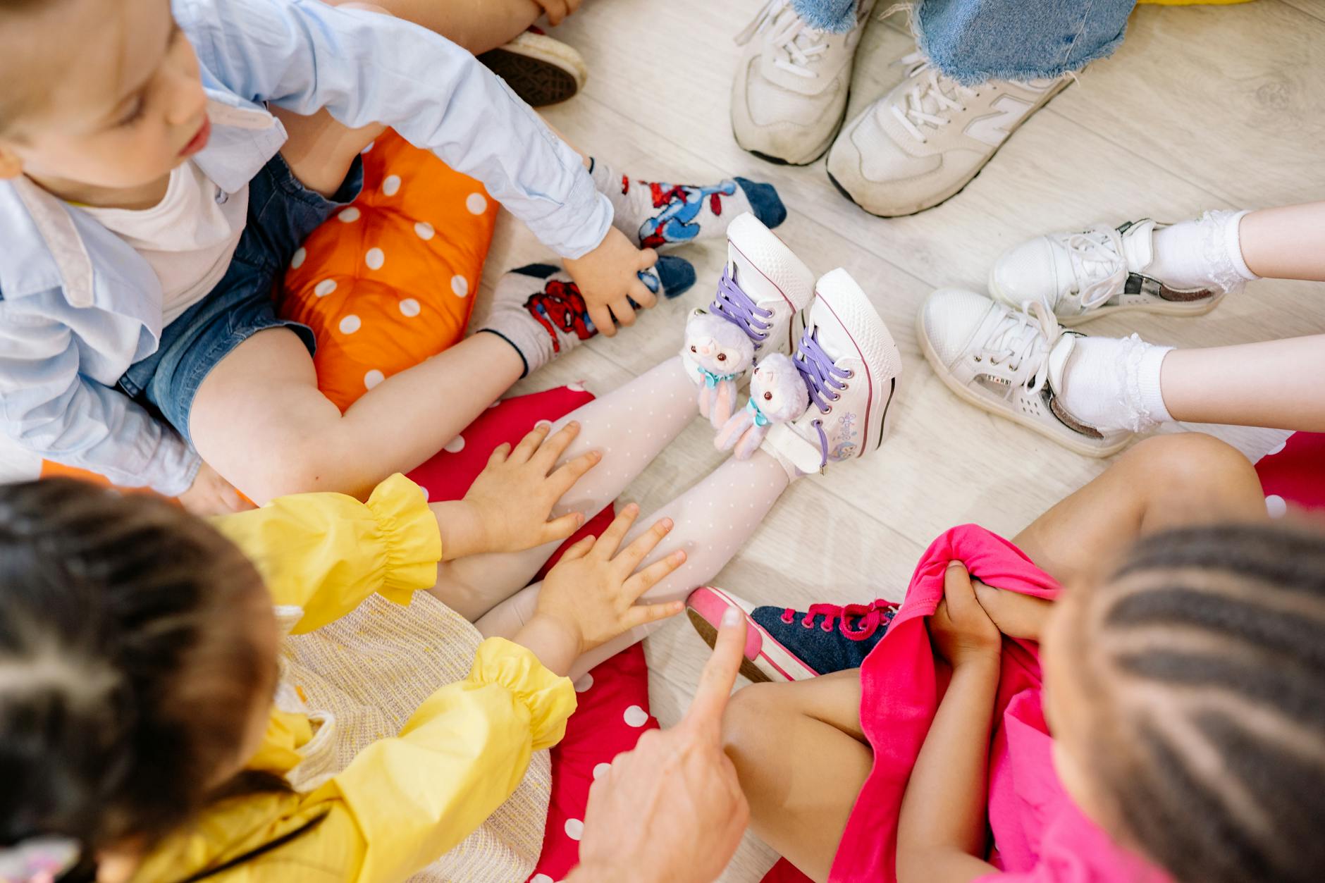Children sitting in a circle on a wooden floor, engaging in fun indoor activities. - preschool sharing activities