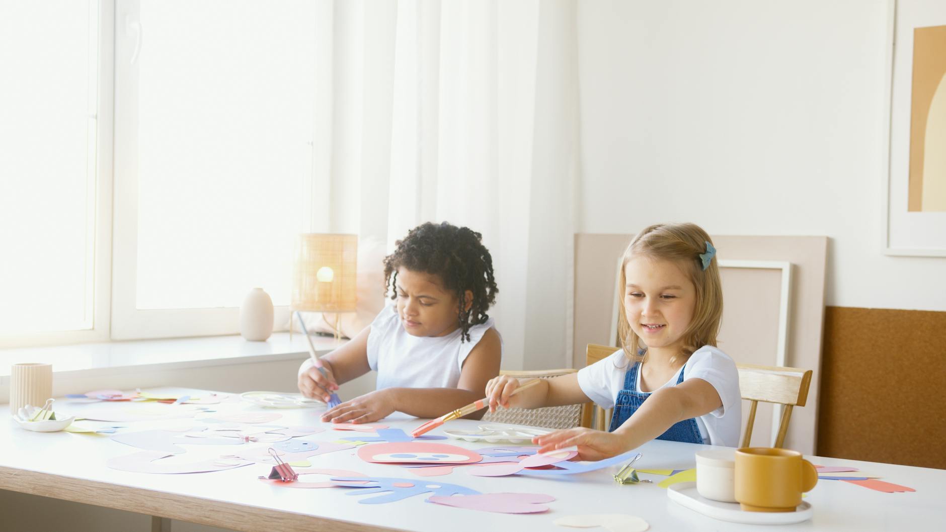 Two children engaged in creative art activities at a table indoors, expressing imagination and fun. - preschool spring crafts