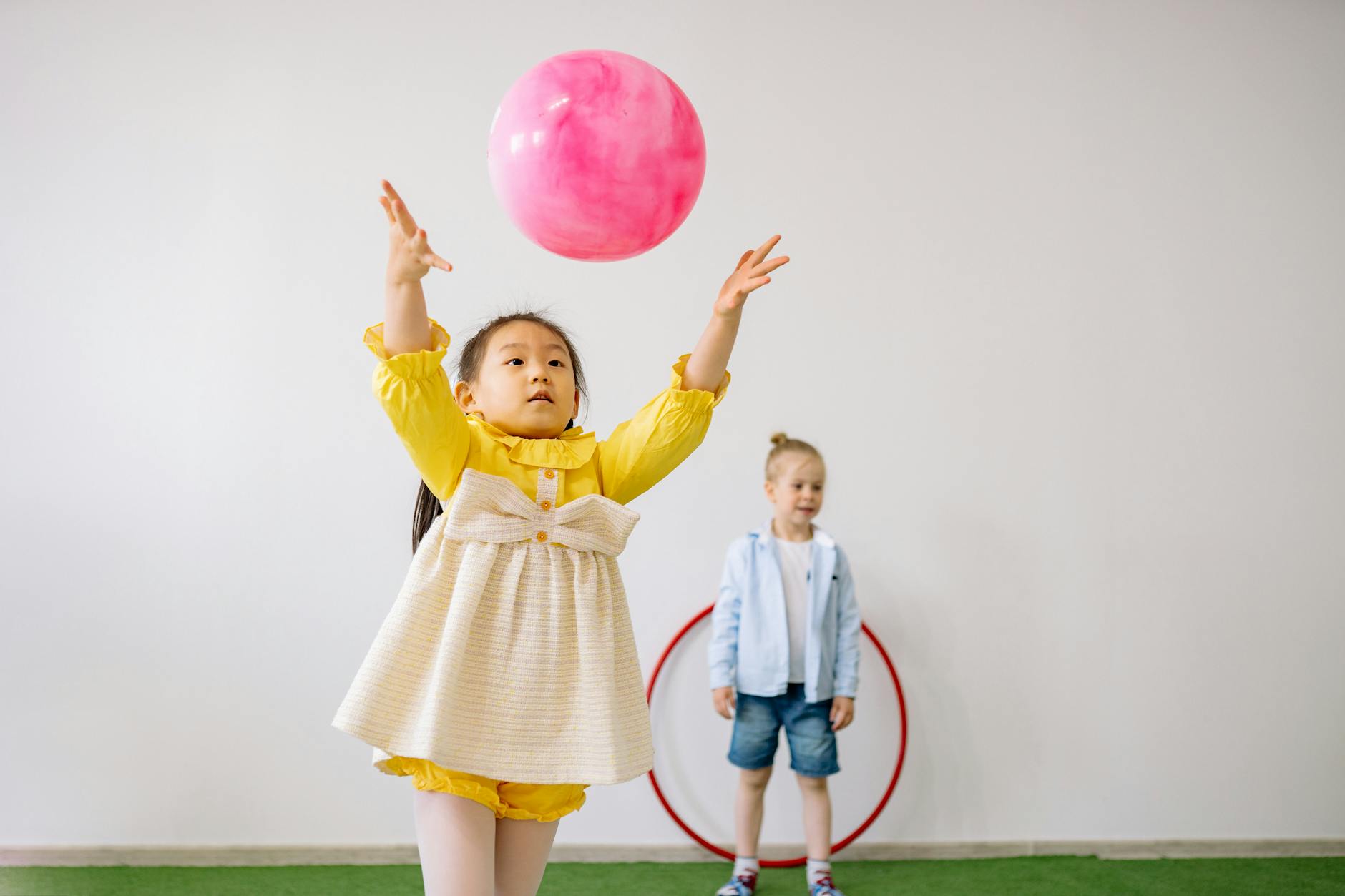 Two children enjoying playtime with balloons in a bright indoor setting. - preschooler self identity