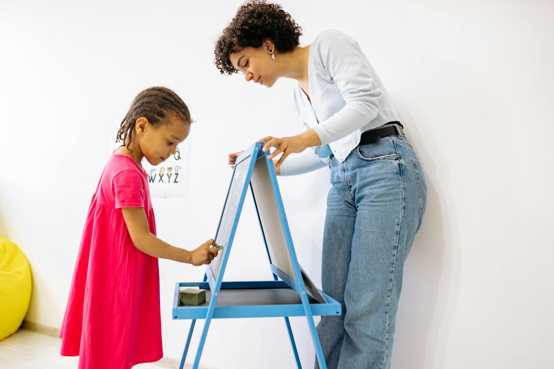 A child and teacher interact at a chalkboard, fostering education and creativity. - preschooler self identity