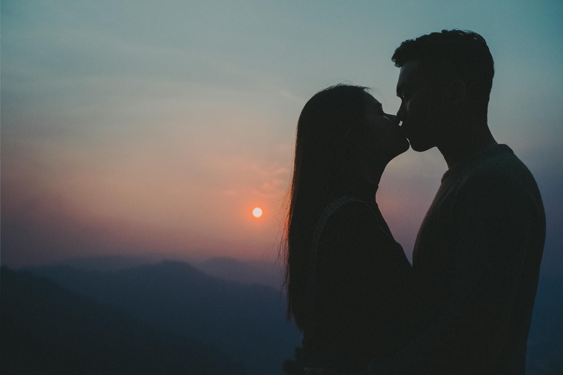 Silhouette of a couple kissing during a breathtaking sunset with scenic mountains. - rekindle relationship passion