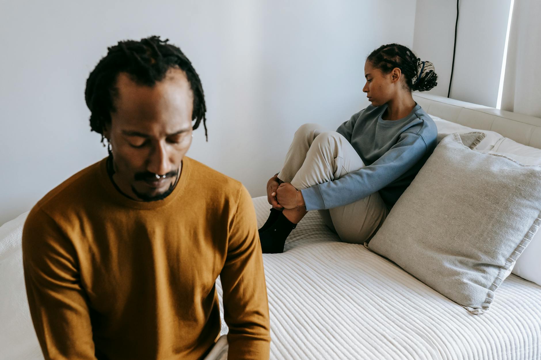 Young black couple in casual outfit spending time on bed with sad face in daytime at home - relationship boredom therapy