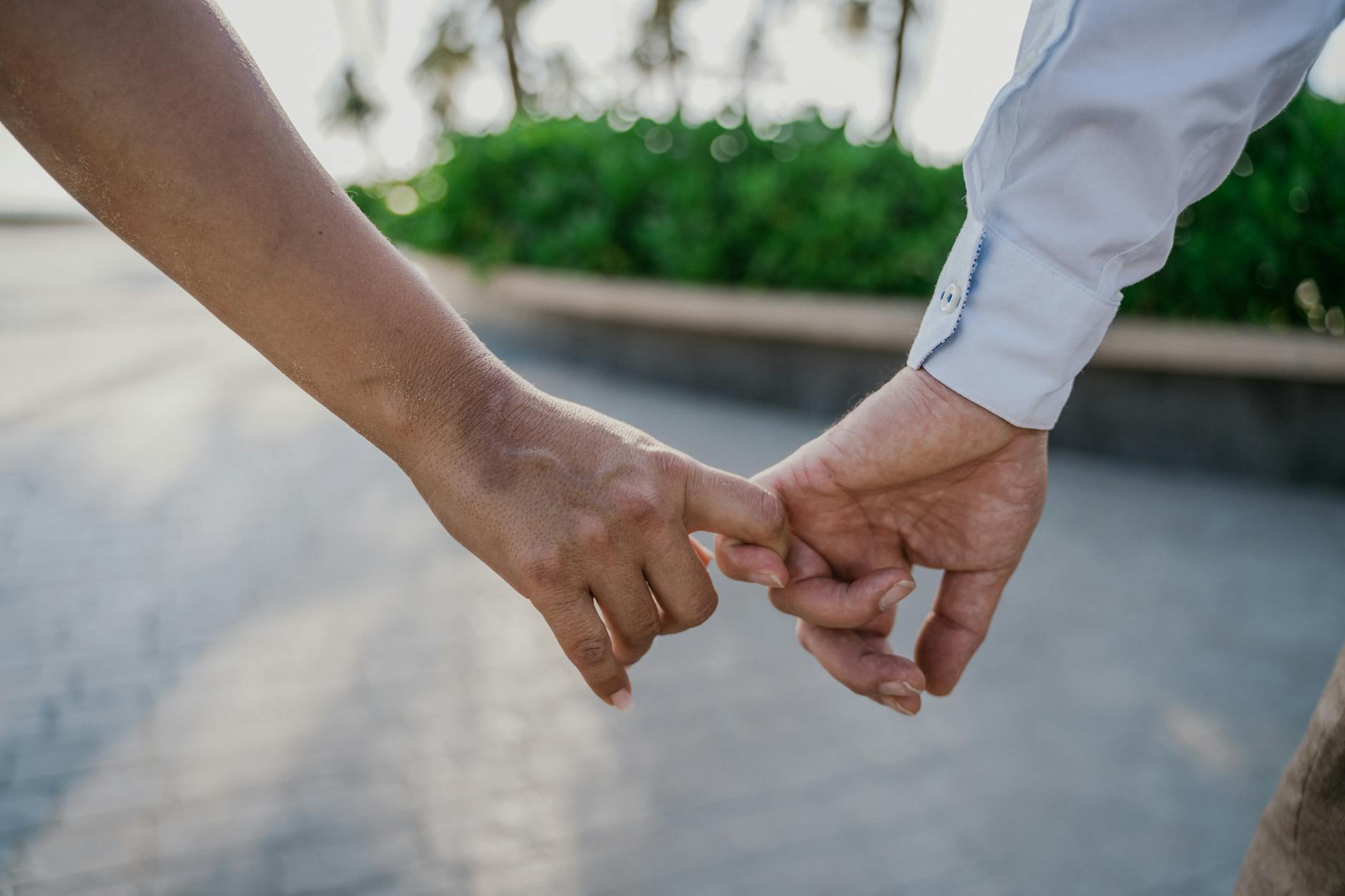 Close-up of a couple gently holding hands outdoors, symbolizing love and connection. - relationship check in