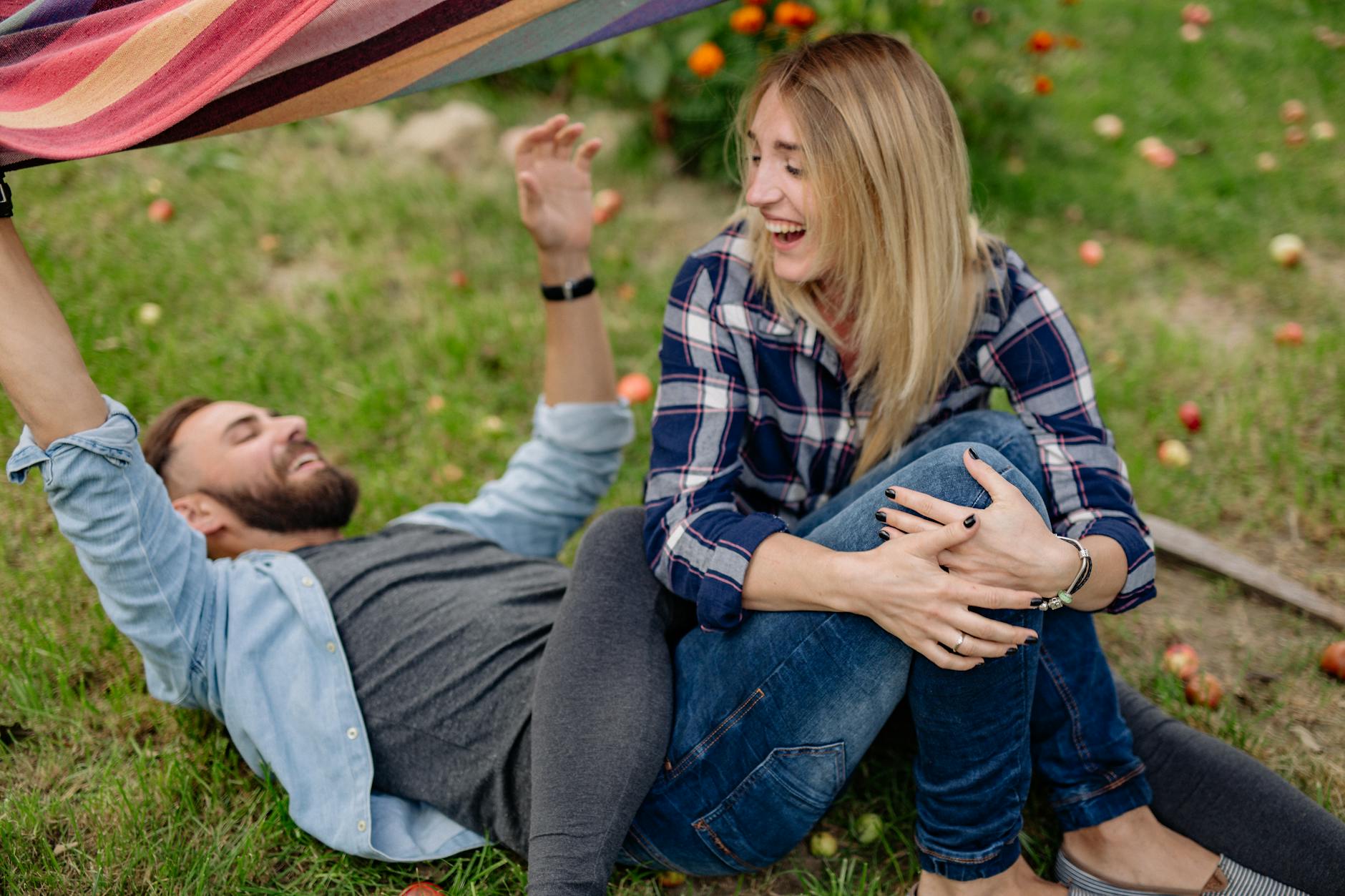 A joyful couple enjoying a playful moment outdoors on the grass, surrounded by apples. - relationship renewal ideas