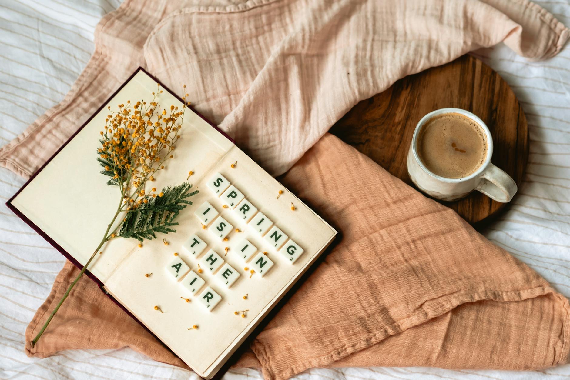 Flat lay of coffee and floral decor with 'Spring is in the air' scrabble message. - spring slump therapy