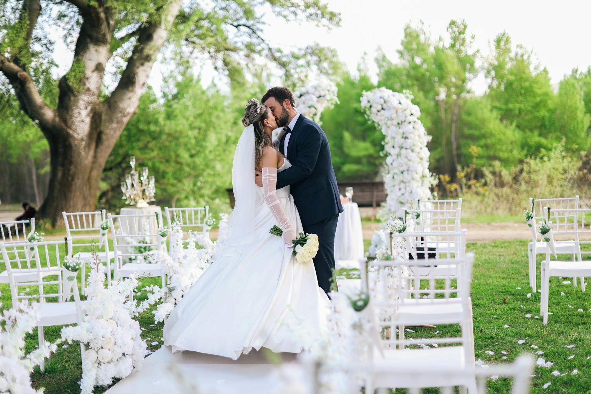 Bride and groom sharing a kiss at their outdoor spring wedding ceremony with elegant decor. - spring wedding survival