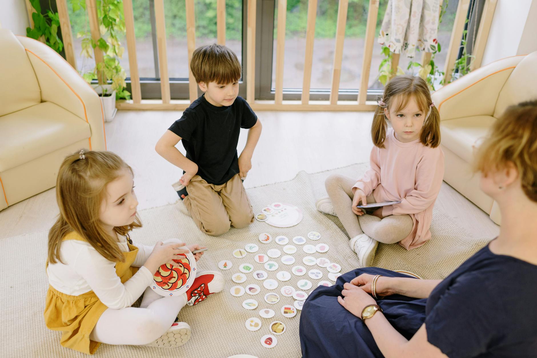 Group of children playing educational games indoors with a teacher. - teach empathy preschoolers