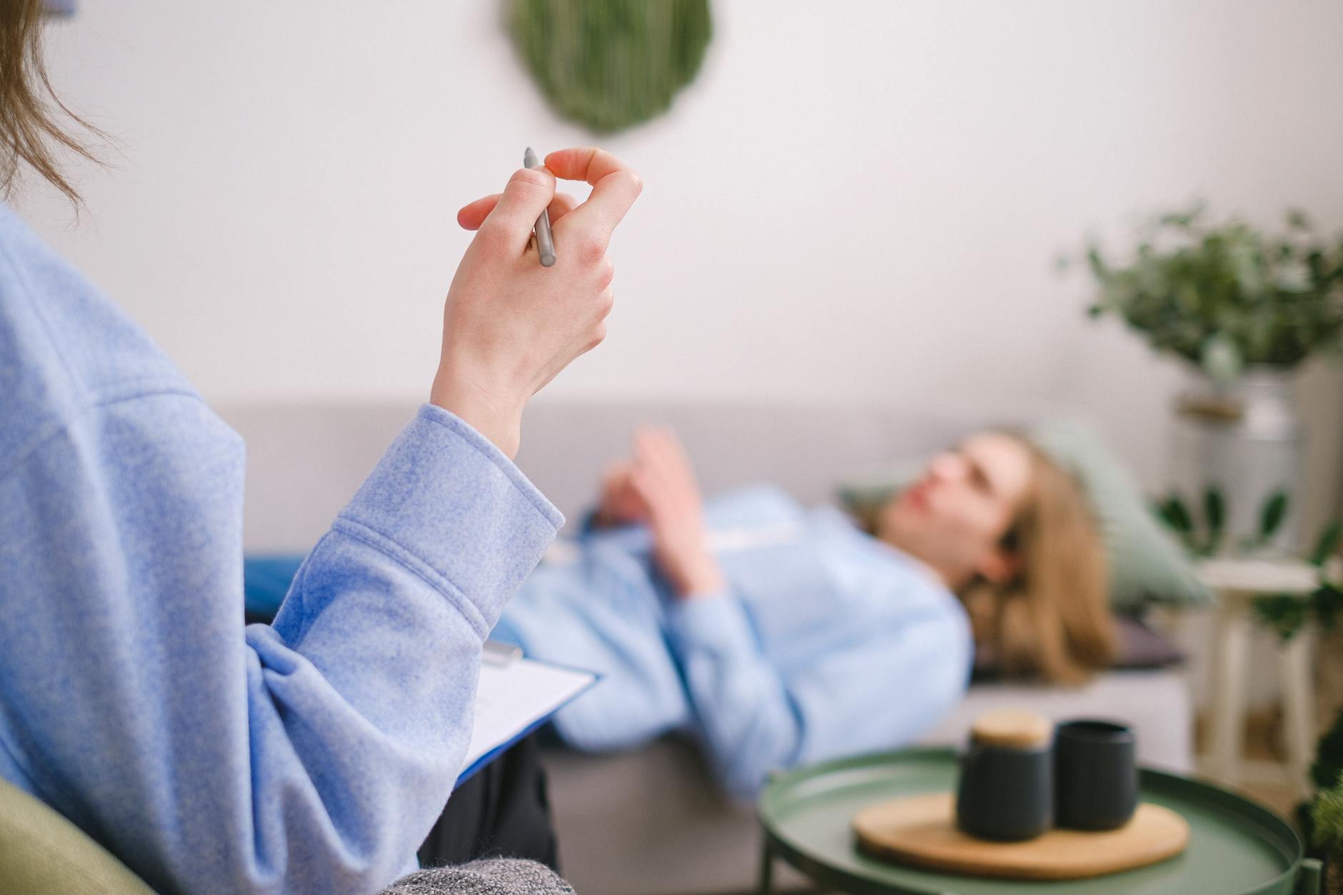 Therapist taking notes during a therapy session with a relaxed client lying on a couch. - therapy stuck breakthrough