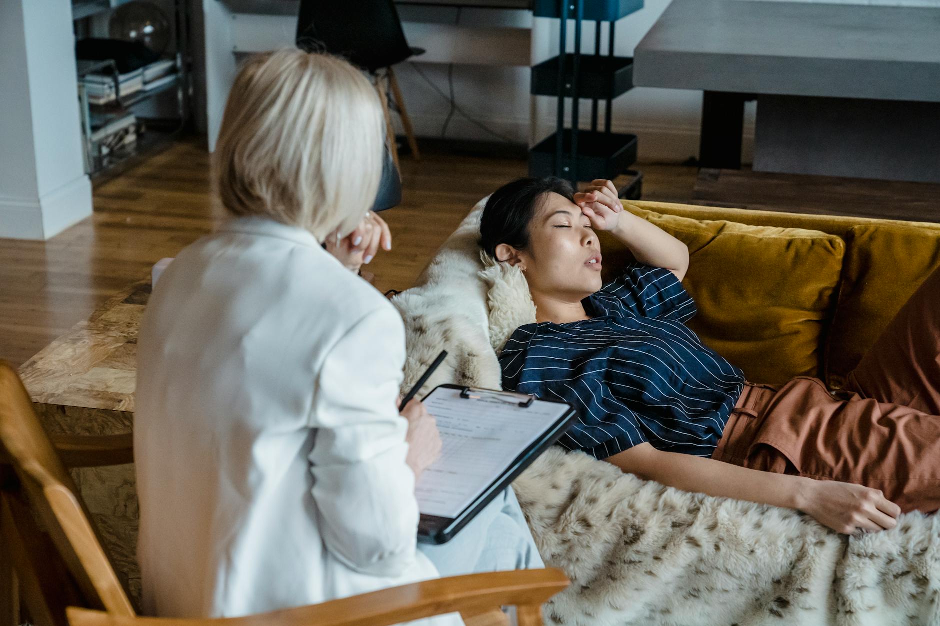 Woman in therapy session lying on couch, discussing emotions with a therapist taking notes. - therapy stuck breakthrough