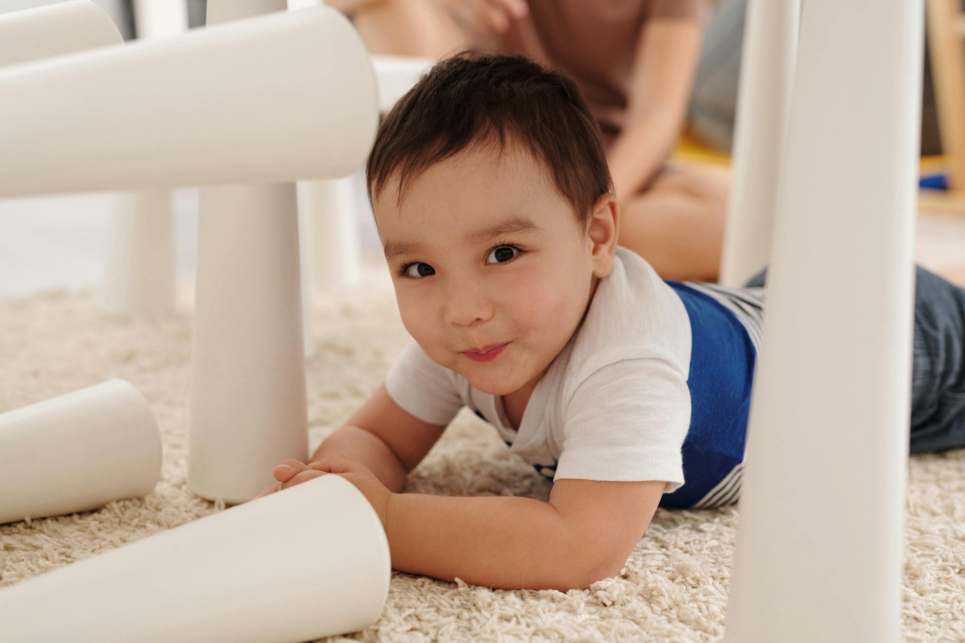 Cute young child enjoying playtime on a soft rug indoors, showcasing playful innocence. - toddler personal space