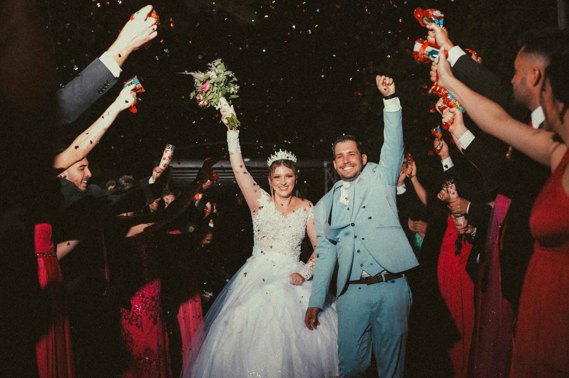 Happy bride and groom celebrating their wedding surrounded by cheering guests with confetti. - wedding stress management