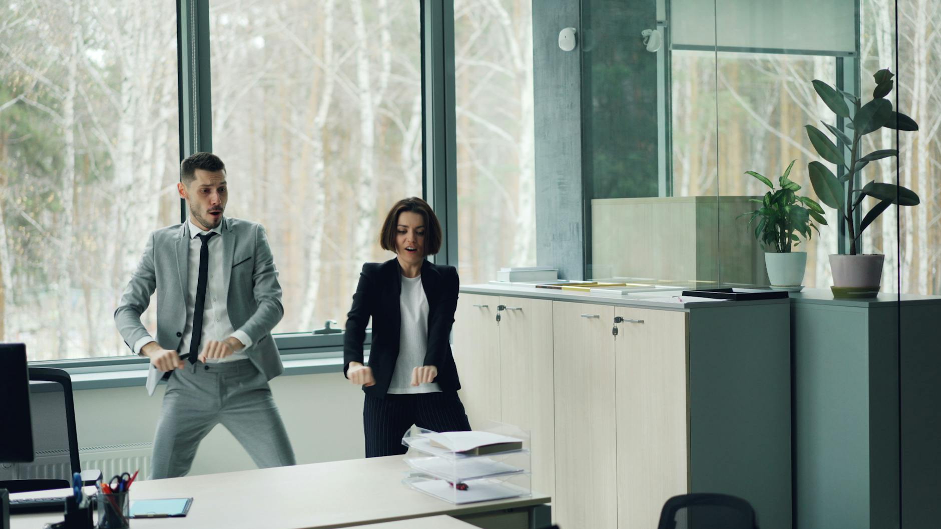 Two adults dance in a modern office space with large windows. - wedding stress relief