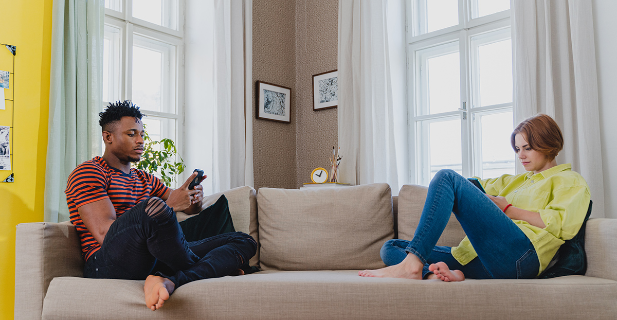 Couple engrossed in their smartphones, indicating negative effects of excessive social media use on relationships.