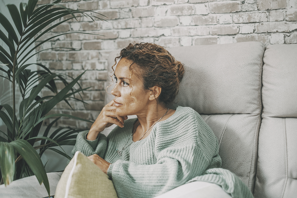 Thoughtful woman on sofa illustrating the need on how to stop overthinking relationship issues.