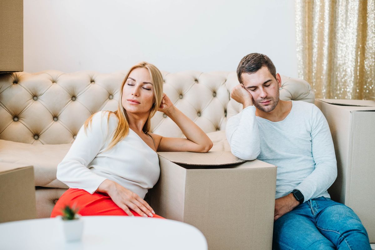 Couple sitting far apart on a couch, signs of falling out of love